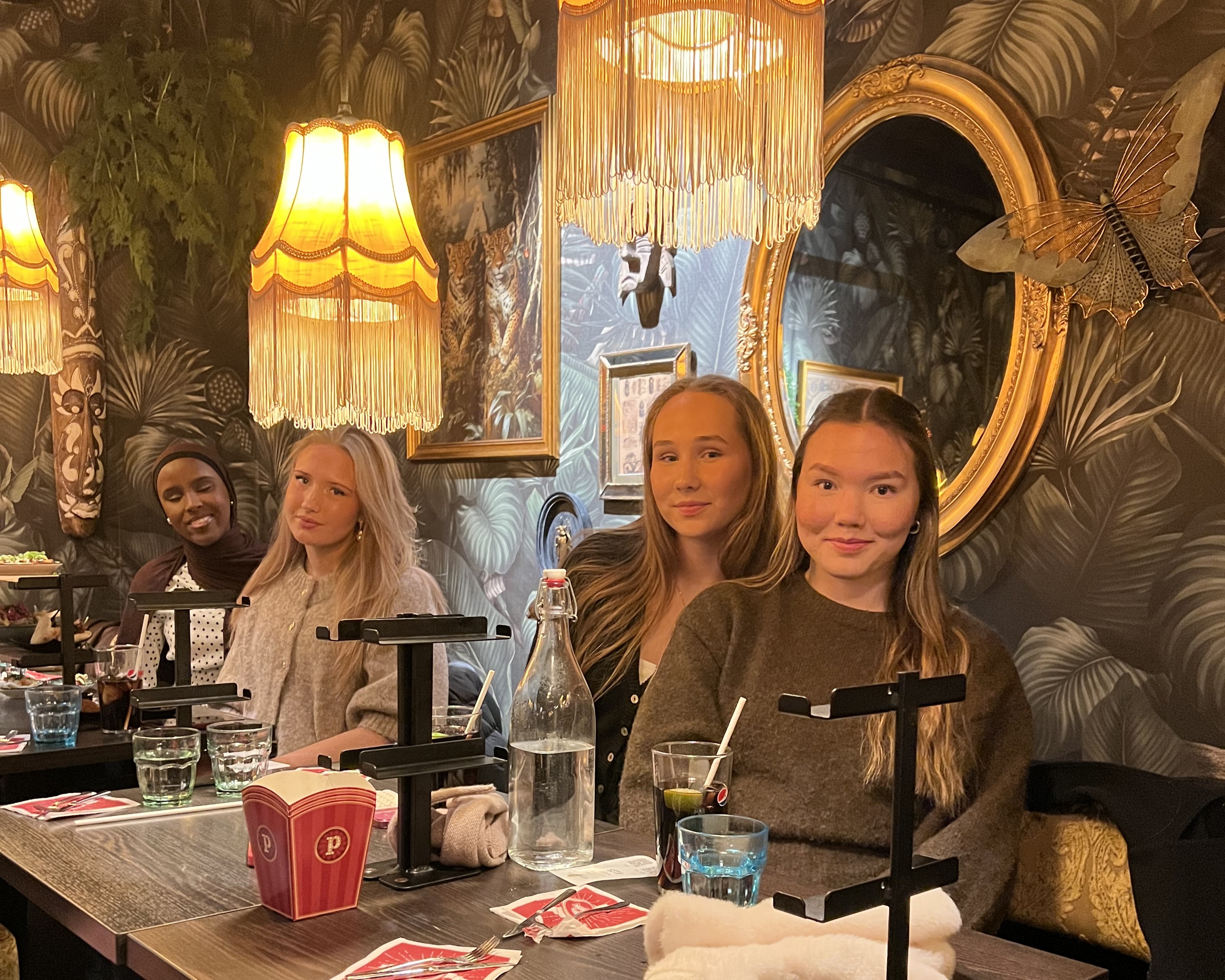 En gruppe personr som sitter ved et bord med drikke og mat