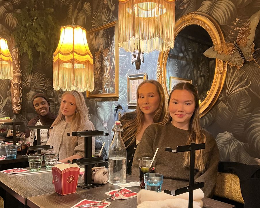 En gruppe personr som sitter ved et bord med drikke og mat En gruppe personr som sitter ved et bord med drikke og mat