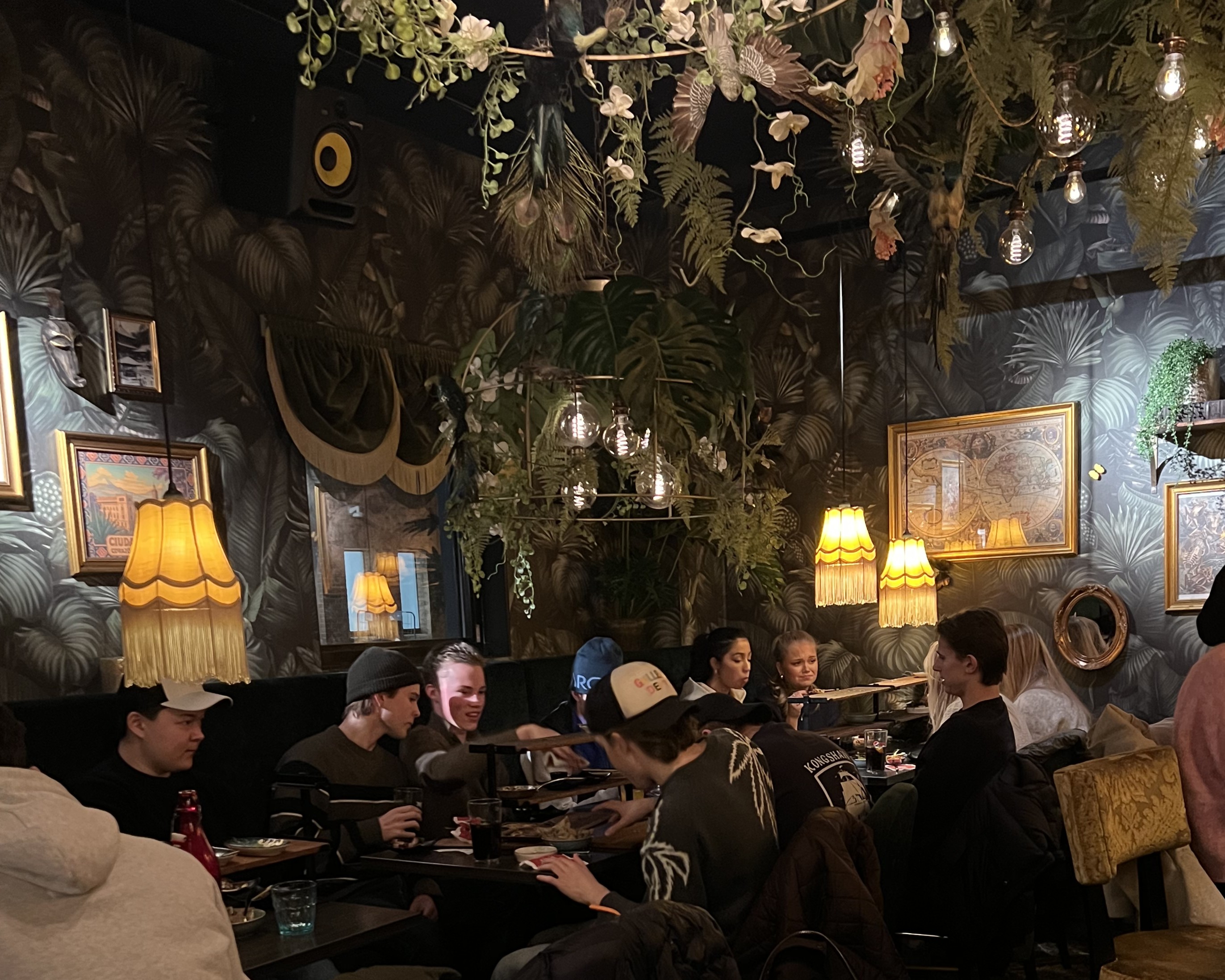 en gruppe mennesker som sitter ved et bord med en lysekrone over seg