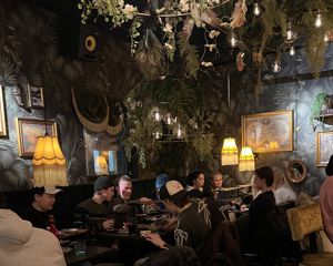 en gruppe mennesker som sitter ved et bord med en lysekrone over seg