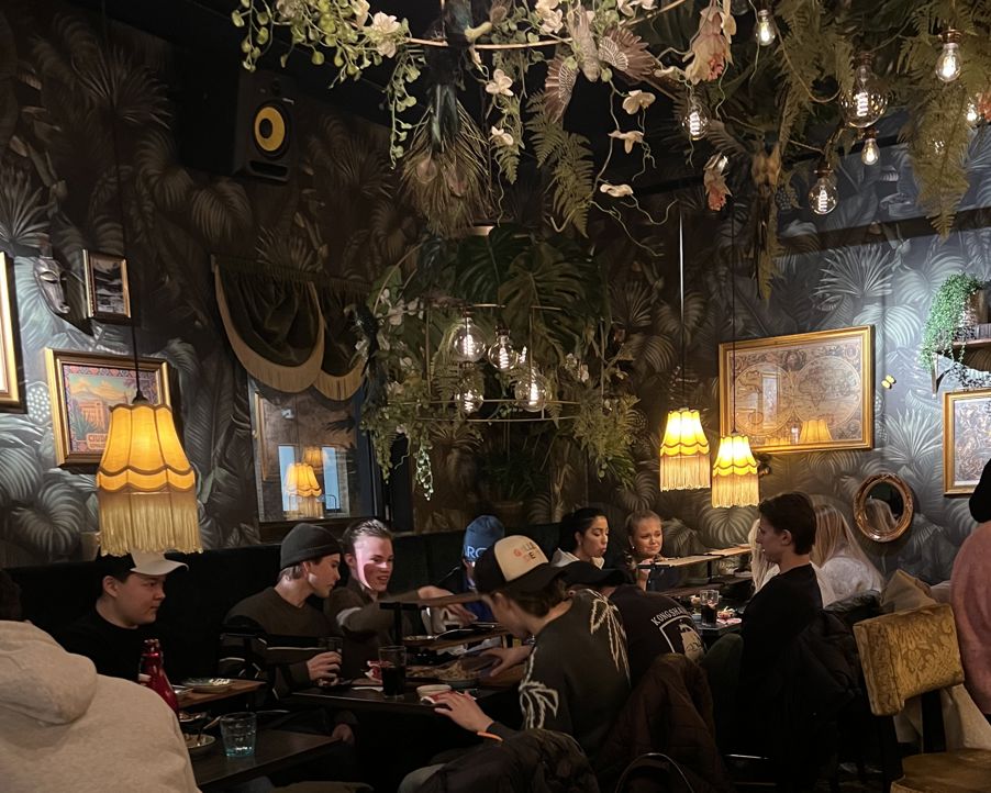 en gruppe mennesker som sitter ved et bord med en lysekrone over seg en gruppe mennesker som sitter ved et bord med en lysekrone over seg