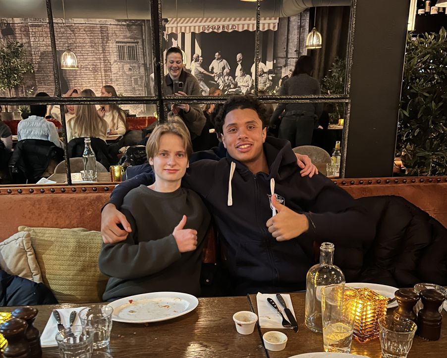 en person og en person som sitter ved et bord med en person bak seg en person og en person som sitter ved et bord med en person bak seg