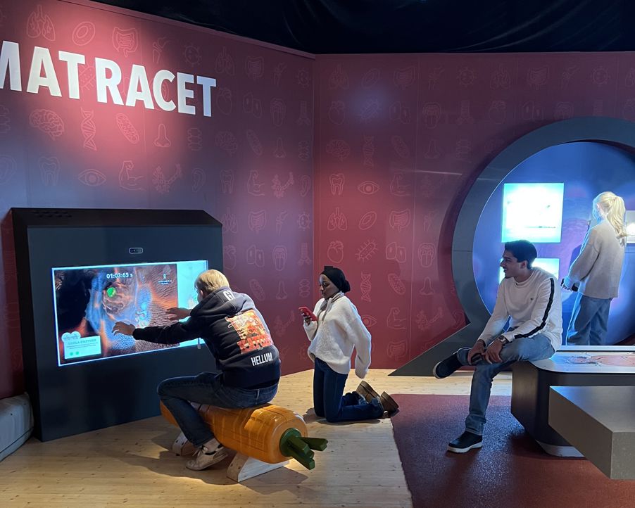 En gruppe mennesker som sitter på en benk foran en TV En gruppe mennesker som sitter på en benk foran en TV