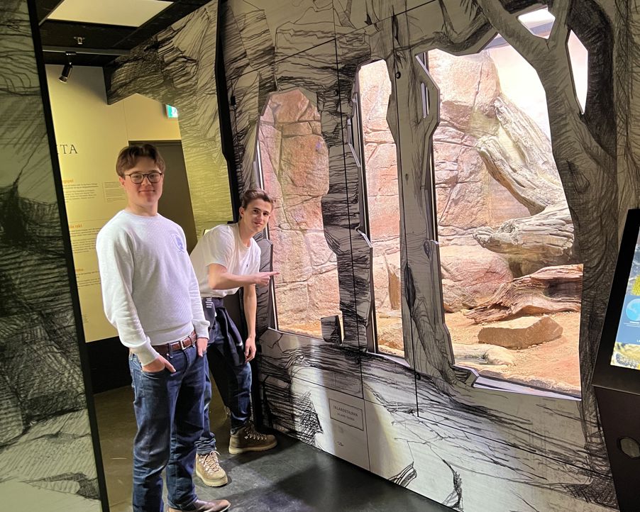 et par menn som sto i et rom med en stor steinvegg et par menn som sto i et rom med en stor steinvegg