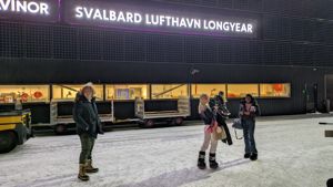 en gruppe mennesker som står foran en bygning med et skilt