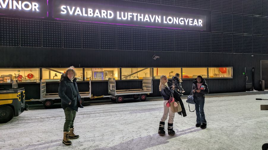 en gruppe mennesker som står foran en bygning med et skilt en gruppe mennesker som står foran en bygning med et skilt