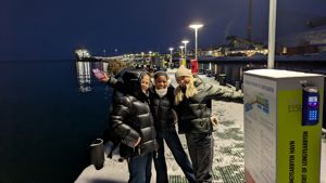 en gruppe mennesker som poserer for et bilde ved siden av et skilt
