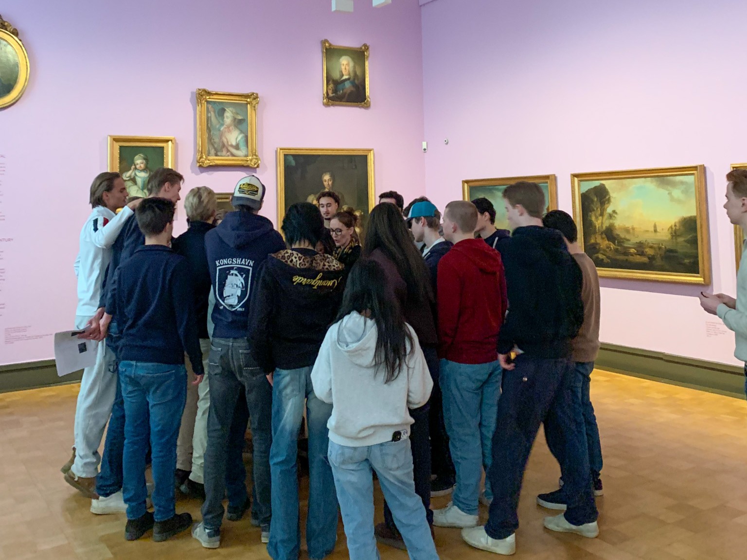 en gruppe mennesker som står i et rom med kunst på veggen