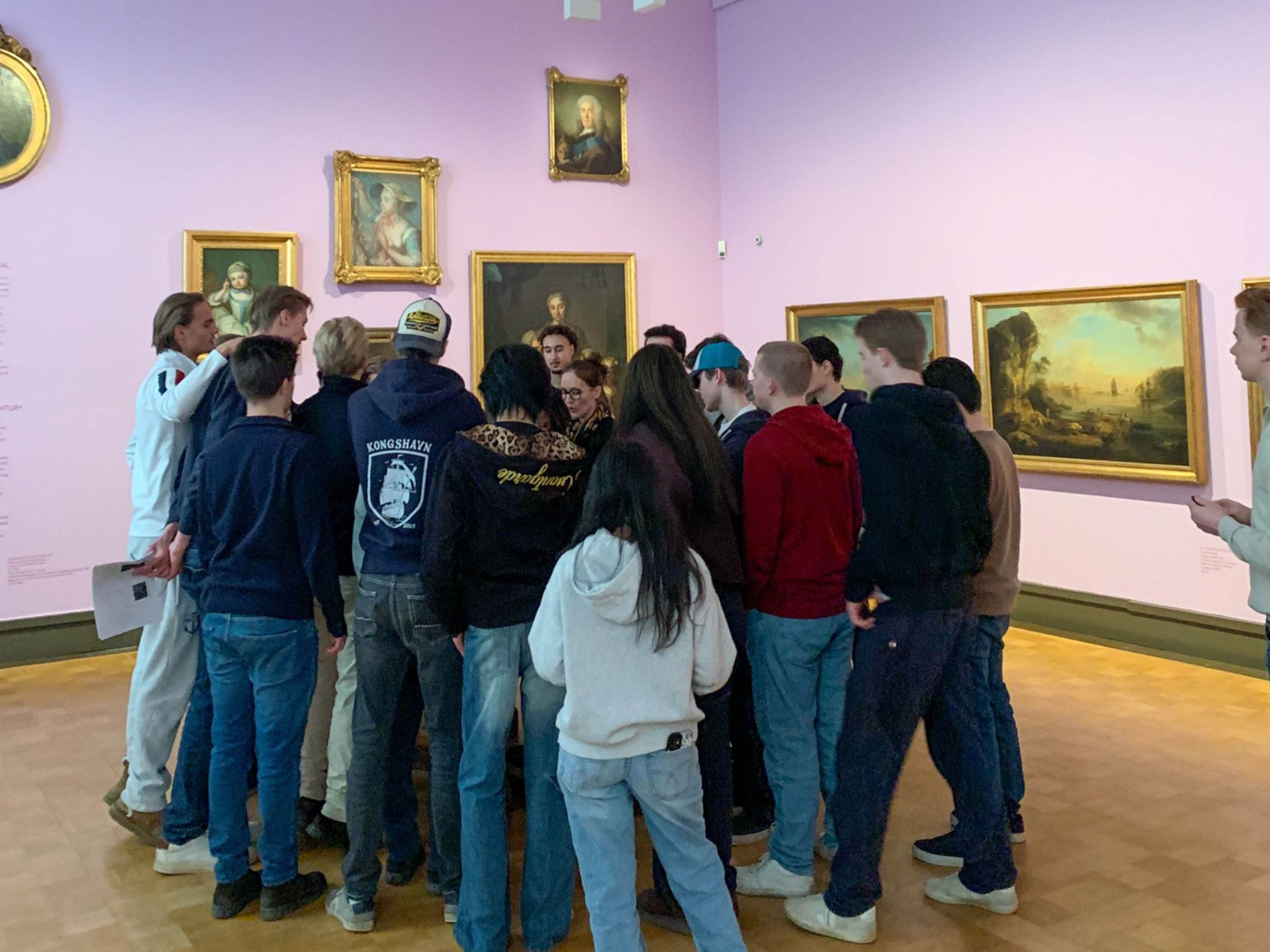 en gruppe mennesker som står i et rom med kunst på veggen