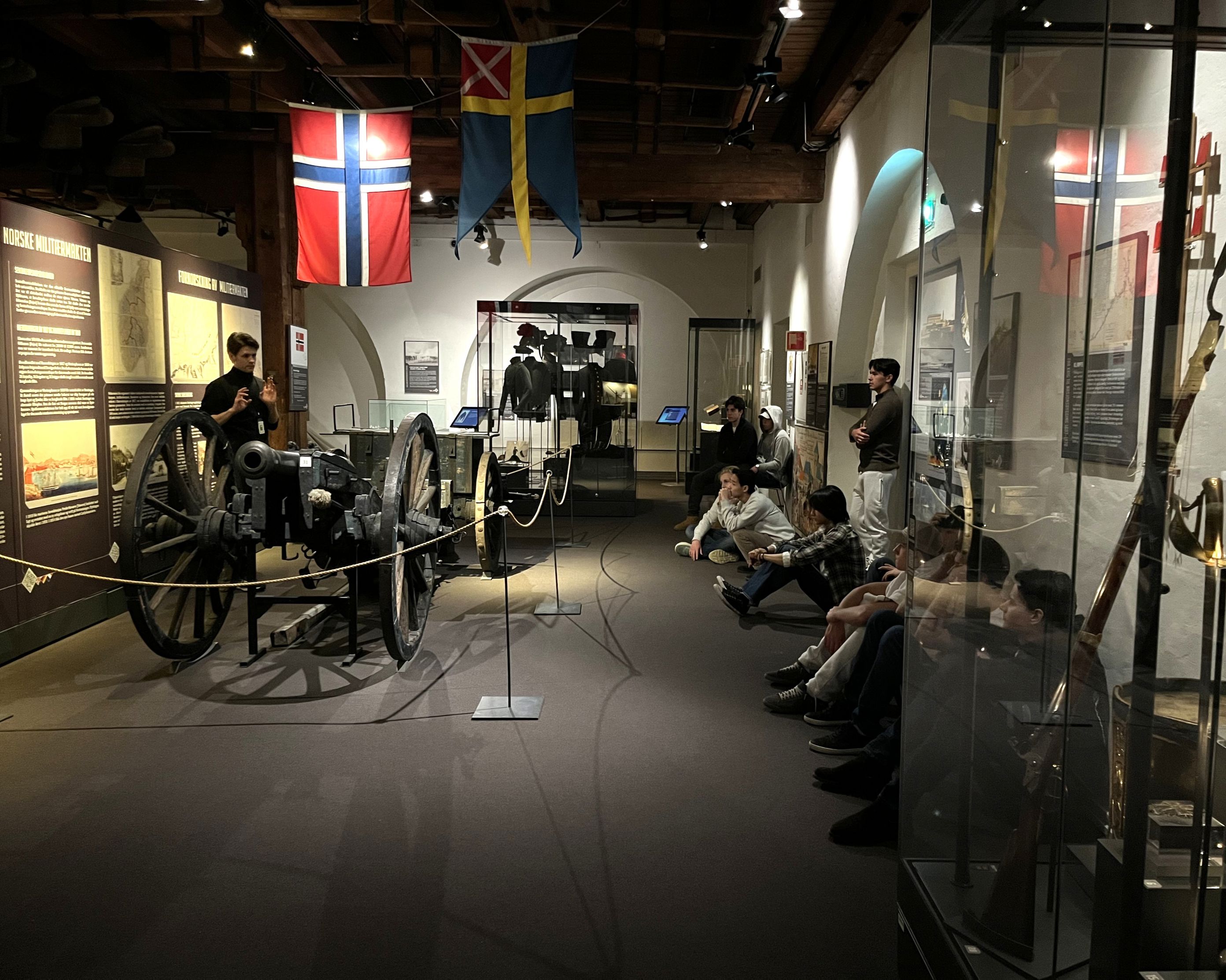 En gruppe mennesker som sitter i et rom med en sykkel og flagg