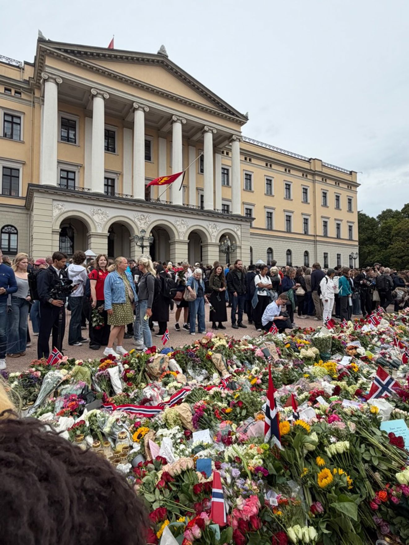 En gruppe mennesker som står foran en bygning med søyler En gruppe mennesker som står foran en bygning med søyler